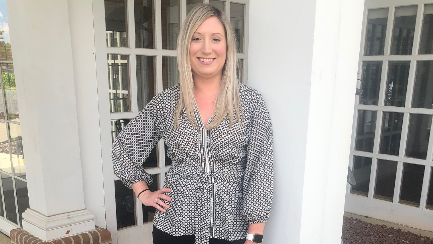 Whitney Anders stands in front of white pillars at the Cancer Center in Easton, Maryland.