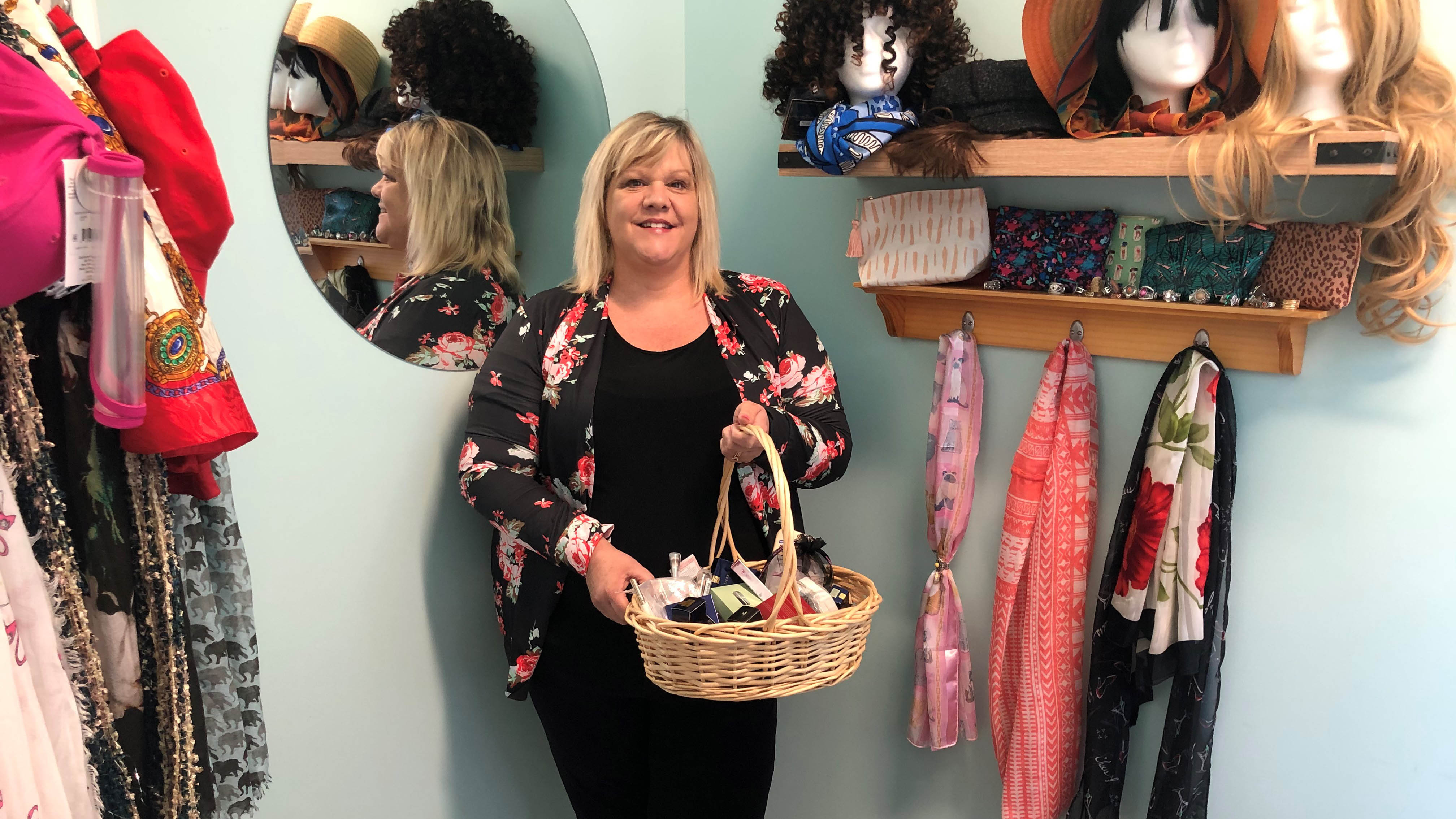 Kim Hardesty stands next to wigs, scarves and other accessories that she uses to help cancer patients feel better about themselves during chemotherapy.