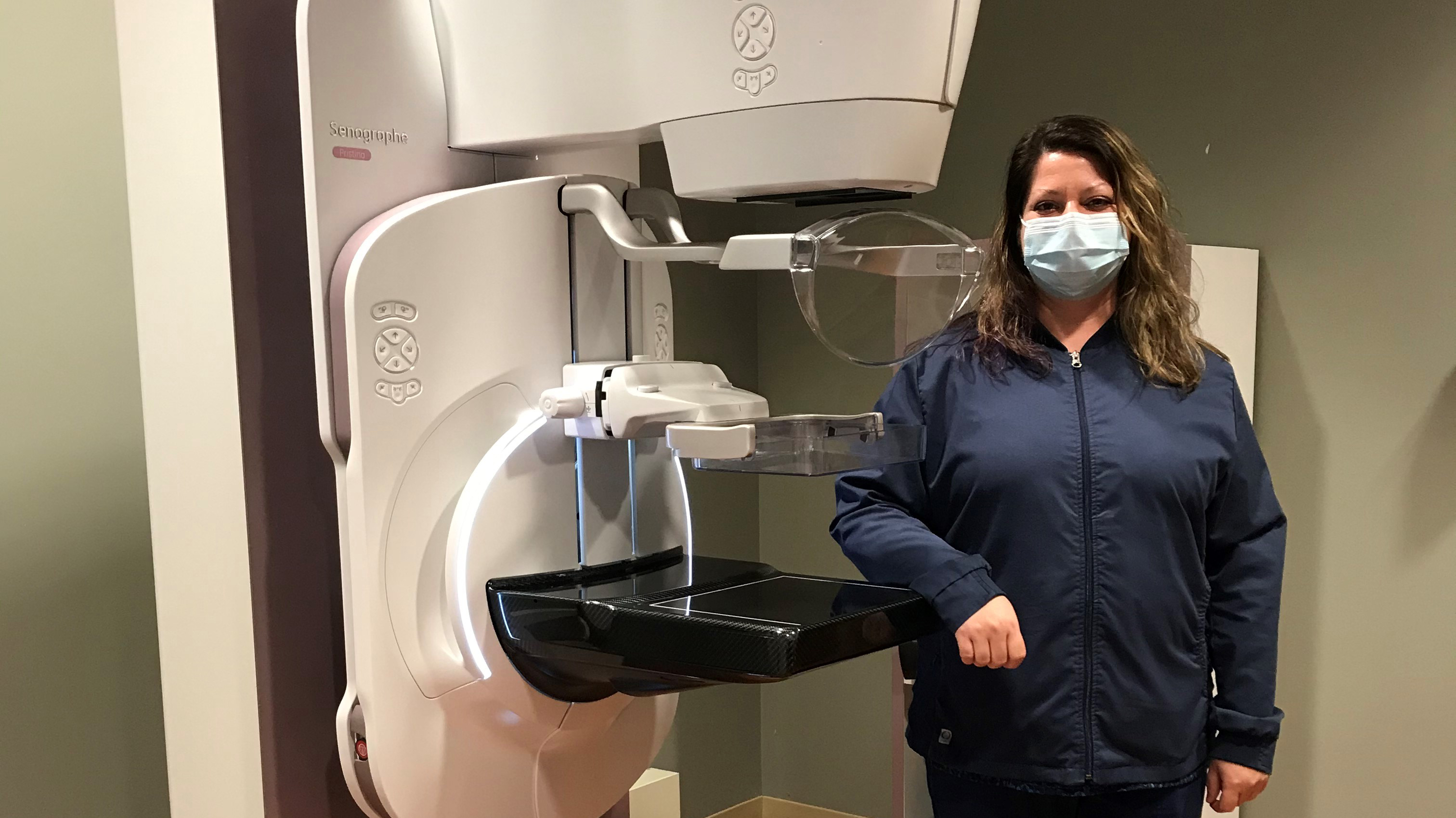Holly Daly stands next to the Senographe Pristina Dueta mammography machine.