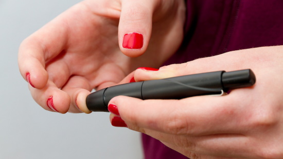 Woman sticking her finger to check blood glucose