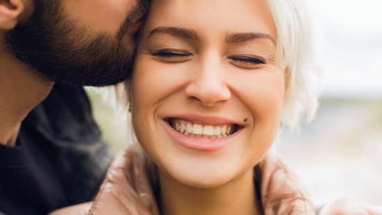 Man kissing a woman on the side of her head