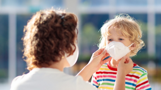 Mother putting mask on young child