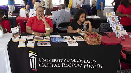 photo of two women sitting at a "University of Maryland Capital Region Health" table at a trade show