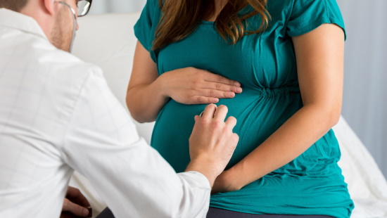 Doctor using stethoscope on pregnant woman