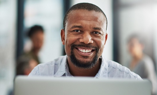 smiling man behind a laptop