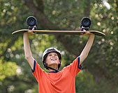 Allied Health jobs image of a kid wearing a helmet and holding a skateboard over their head