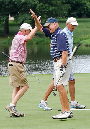 Golf players high five after put