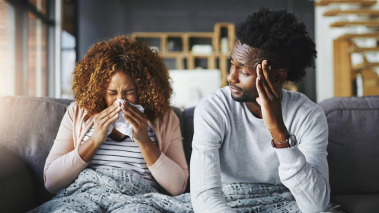 Woman sneezing while a man looks on