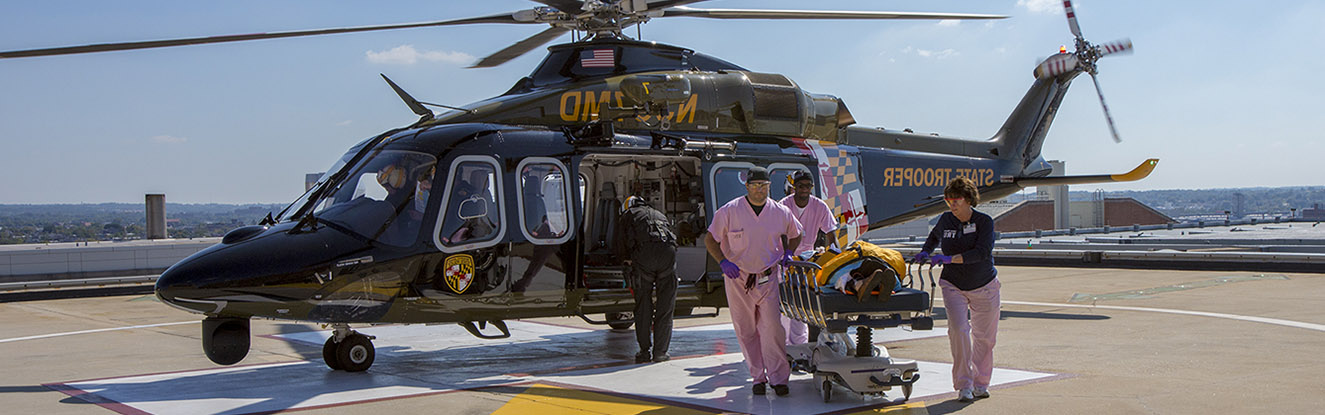 Helicopter on Shock Trauma's roof with medical providers wheeling a patient from the helicopter