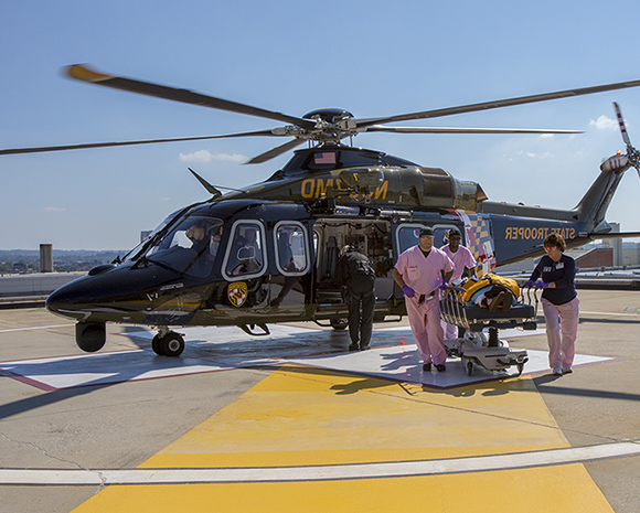 Helicopter on Shock Trauma's roof with medical providers wheeling a patient from the helicopter