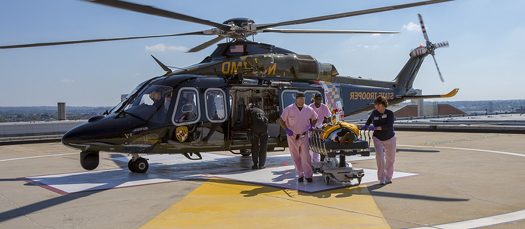 Helicopter on Shock Trauma's roof with medical providers wheeling a patient from the helicopter